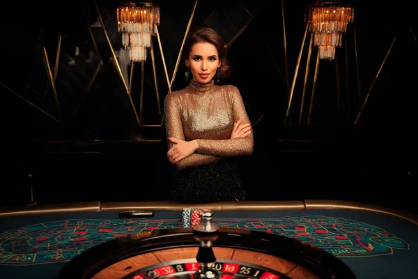 A woman smiling by bright slot machines showing lucky symbols, showcasing the exciting slot offerings at 6777DET.